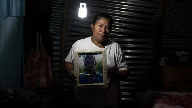 Maria Elena, de El Salvador, sostiene una foto de su hijo muerto por las autoridades