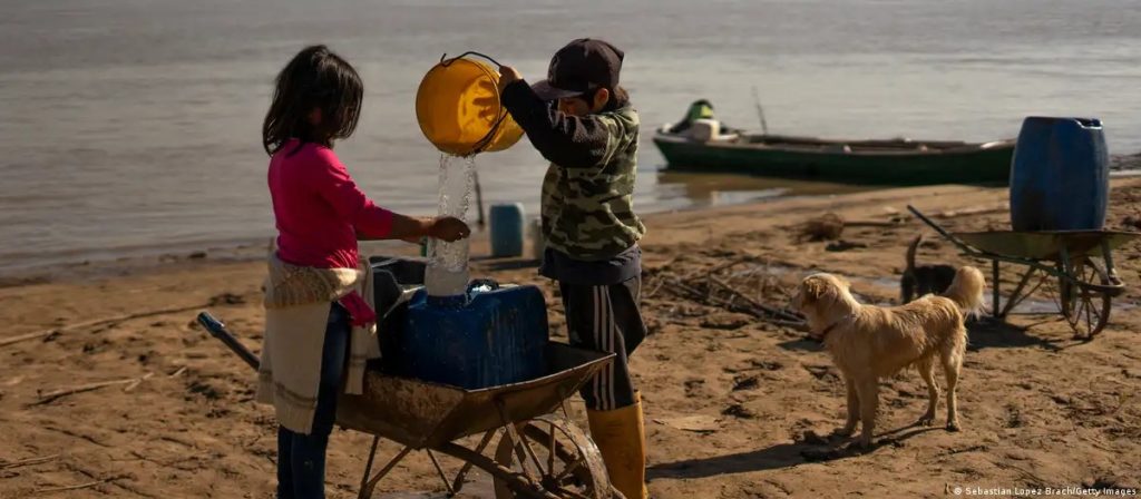 Niños argentinos recogen agua del rio